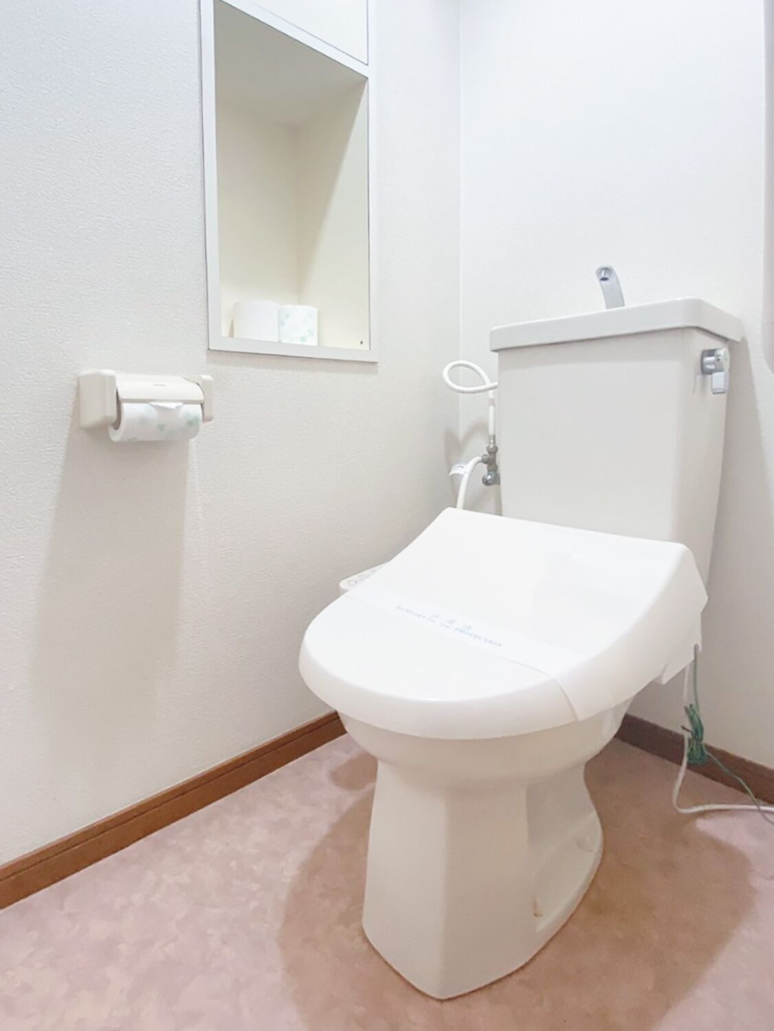 A white toilet with a paper towel holder and a mirror above it.