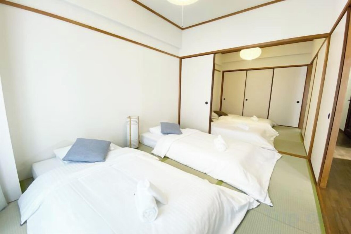 A traditional Japanese-style room with tatami flooring, a low ceiling, and a sliding door leading to a separate area.