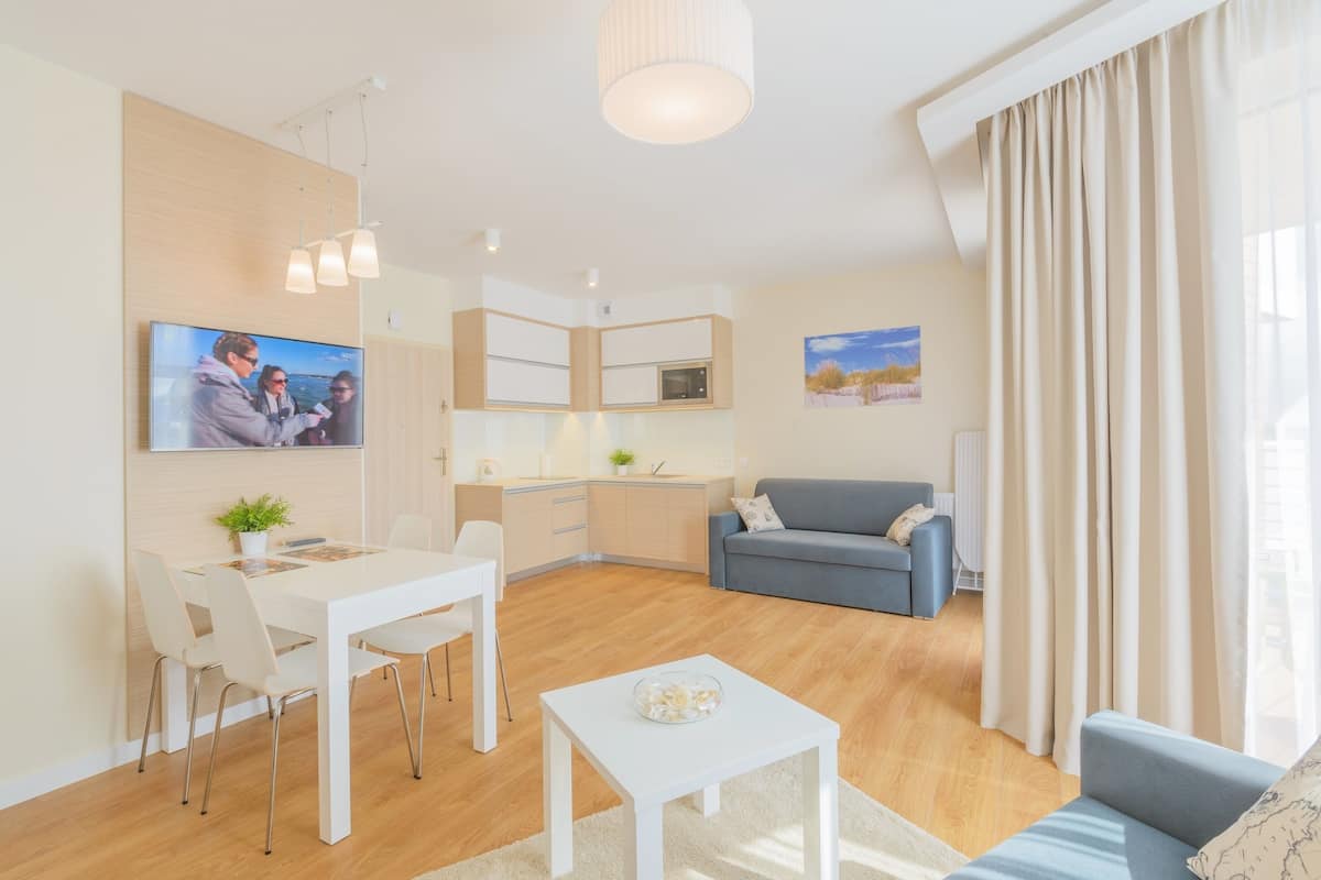 A modern living room with a dining area, a kitchen, and a sofa.