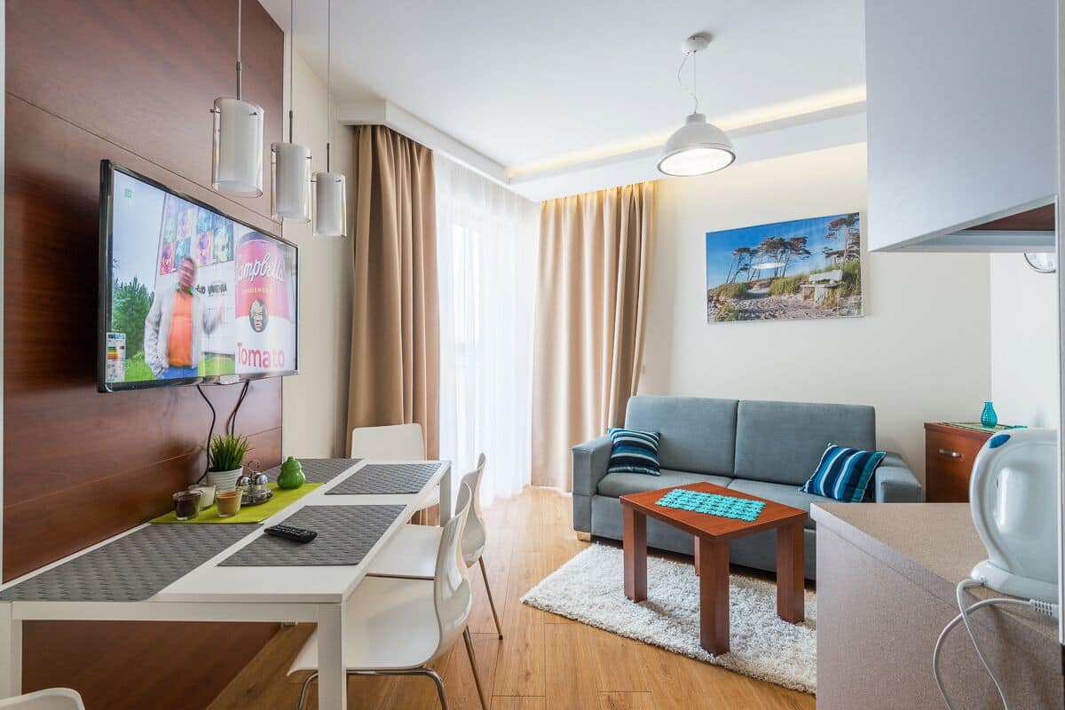 A modern living room with a sofa, a coffee table, and a TV mounted on the wall.