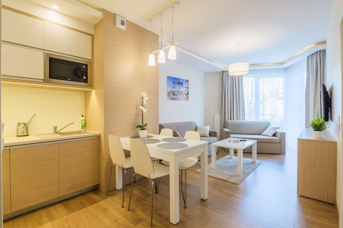 A modern kitchen with a microwave, dining table with chairs, a sofa, and a coffee table.