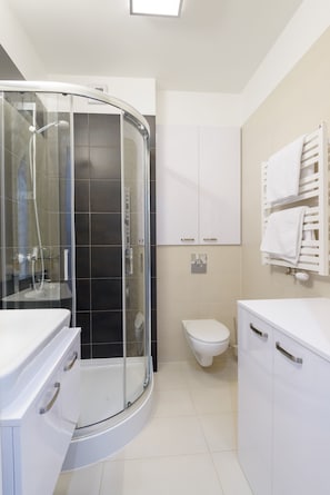 A modern bathroom with a glass-enclosed shower, a toilet, and white cabinetry.
