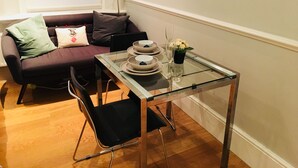 A dining area with a glass table, black chairs, and a sofa with cushions. - 3 Bedroom Apartments Wells Street (London)