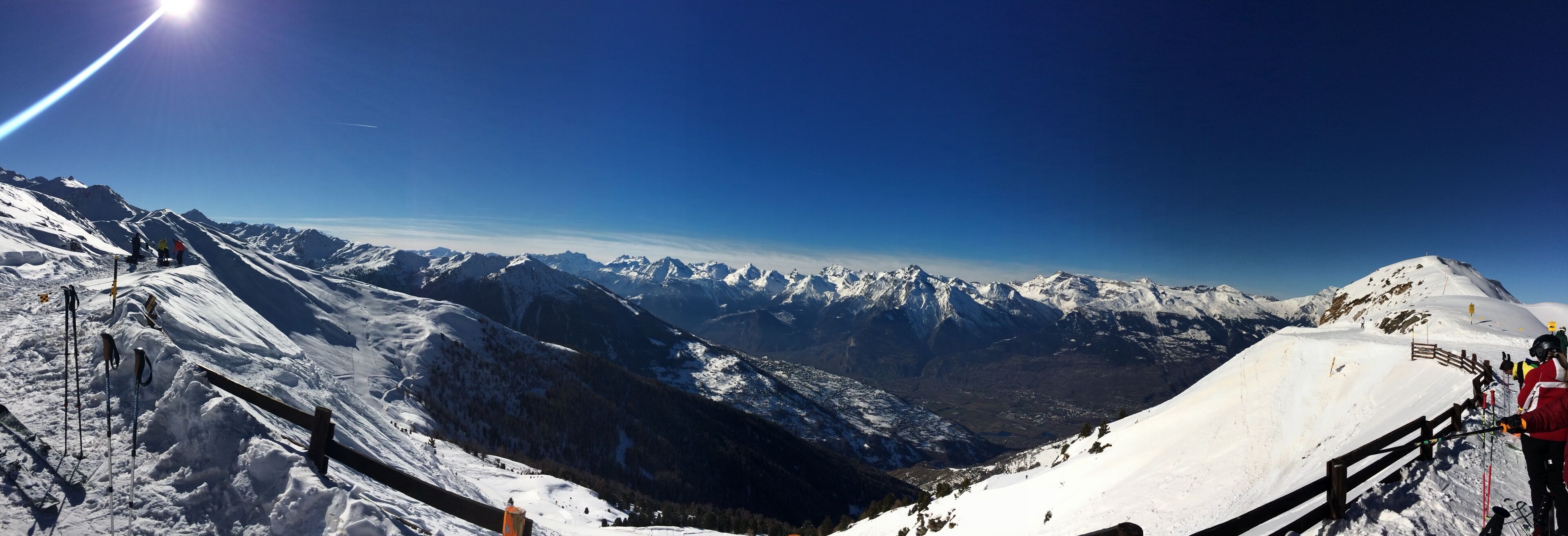 Paesaggio montano innevato con piste da sci e cielo sereno.