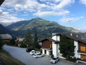 A residential area with houses, parked cars, and a mountain in the background. - IRIS Apartment "Vacation Rental in Veysonnaz, 4 Valleys" (Veysonnaz)