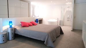 A modern bedroom with a large bed, bedside lamps, a vanity, and a shower area. - Luxury vacation rental SALON DE PROVENCE LS7-351 (Salon-de-Provence)