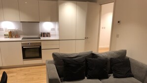 A modern kitchen with white cabinets, a built-in oven, and a countertop with various items. - Luxury 2 Bed 2 Bath Apartments next to kings cross (London)