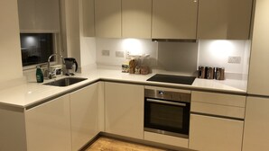 A modern kitchen with white cabinetry, a stainless steel oven, and a black countertop. - Luxury 2 Bed 2 Bath Apartments next to kings cross (London)