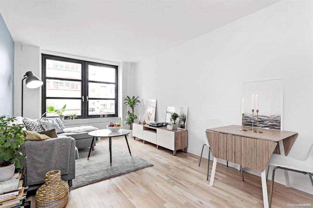 A modern living room with a grey sofa, a round coffee table, a white cabinet, and a wooden desk.