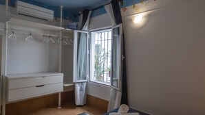 Un dormitorio con ventana, un armario blanco y una cama.