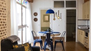 Cocina compacta con comedor, que incluye una mesa redonda, sillas y una lámpara colgante azul.