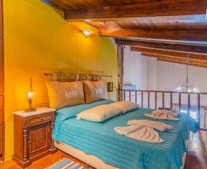 A bedroom with a bed, pillows, a nightstand, and a balcony with a railing.