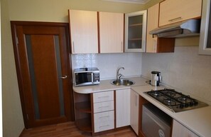 Compact kitchen with a modern design, featuring a stainless steel sink and essential appliances for cooking and preparing beverages.