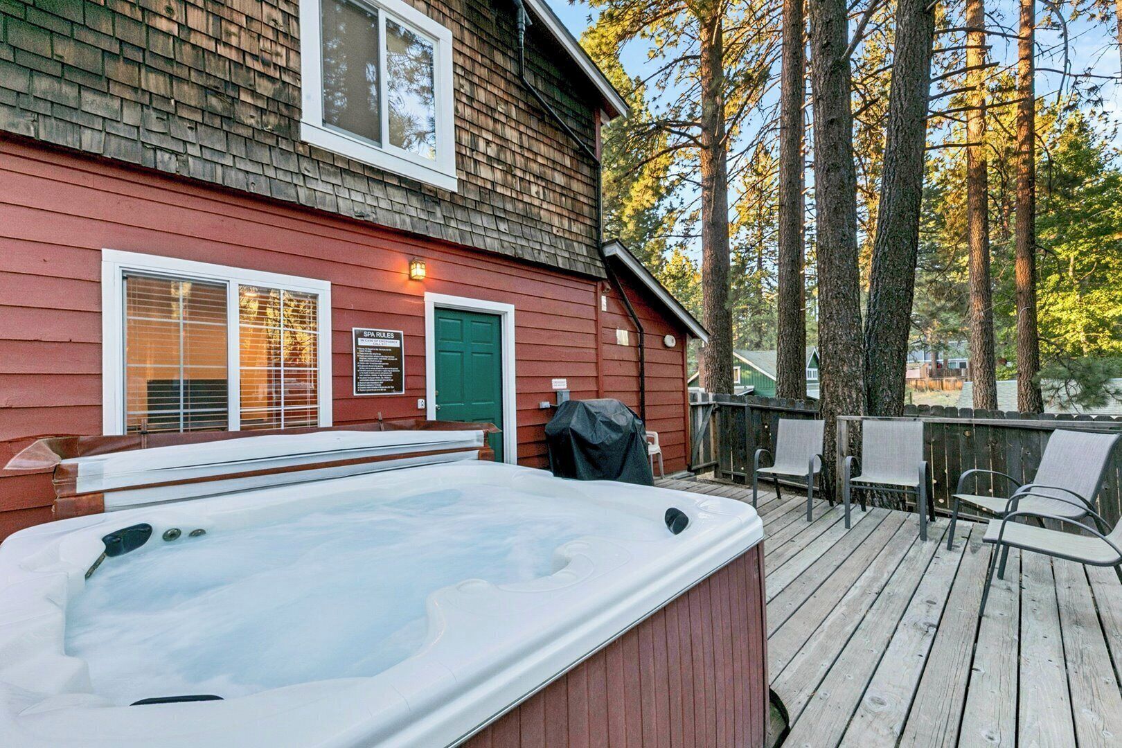 Una cabaña de spa con jacuzzi, sillas de terraza y una puerta verde.