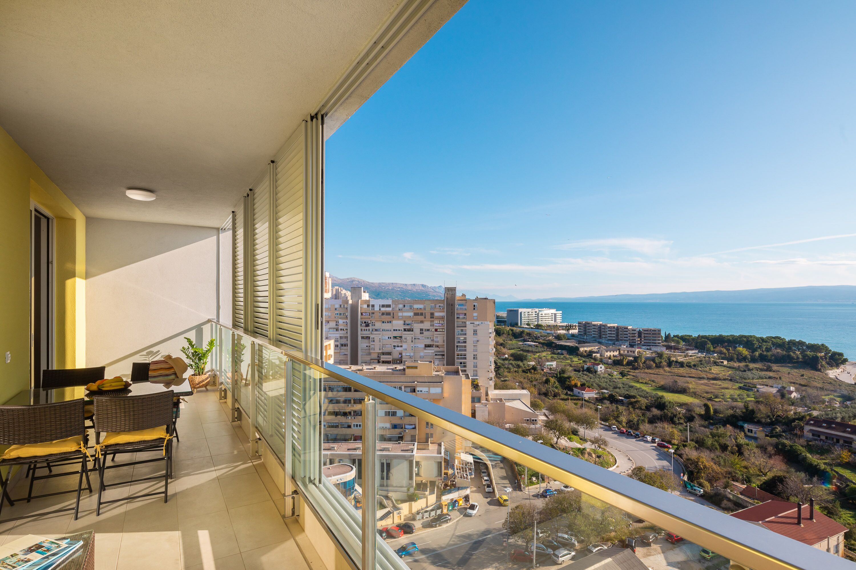 A balcony with a view of a coastal cityscape, including buildings and a body of water.