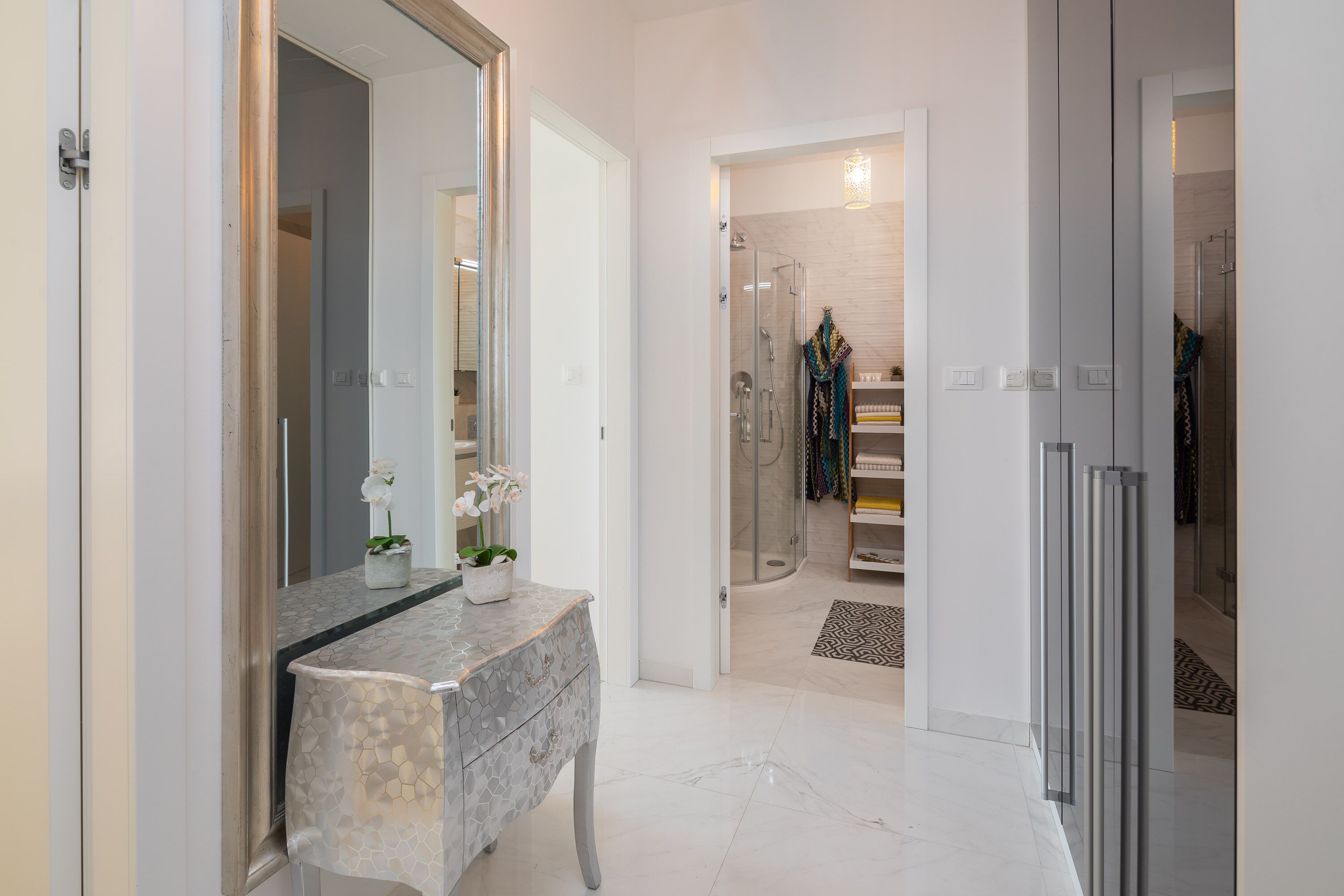 A modern bathroom with a marble vanity, a large mirror, and a glass shower enclosure.