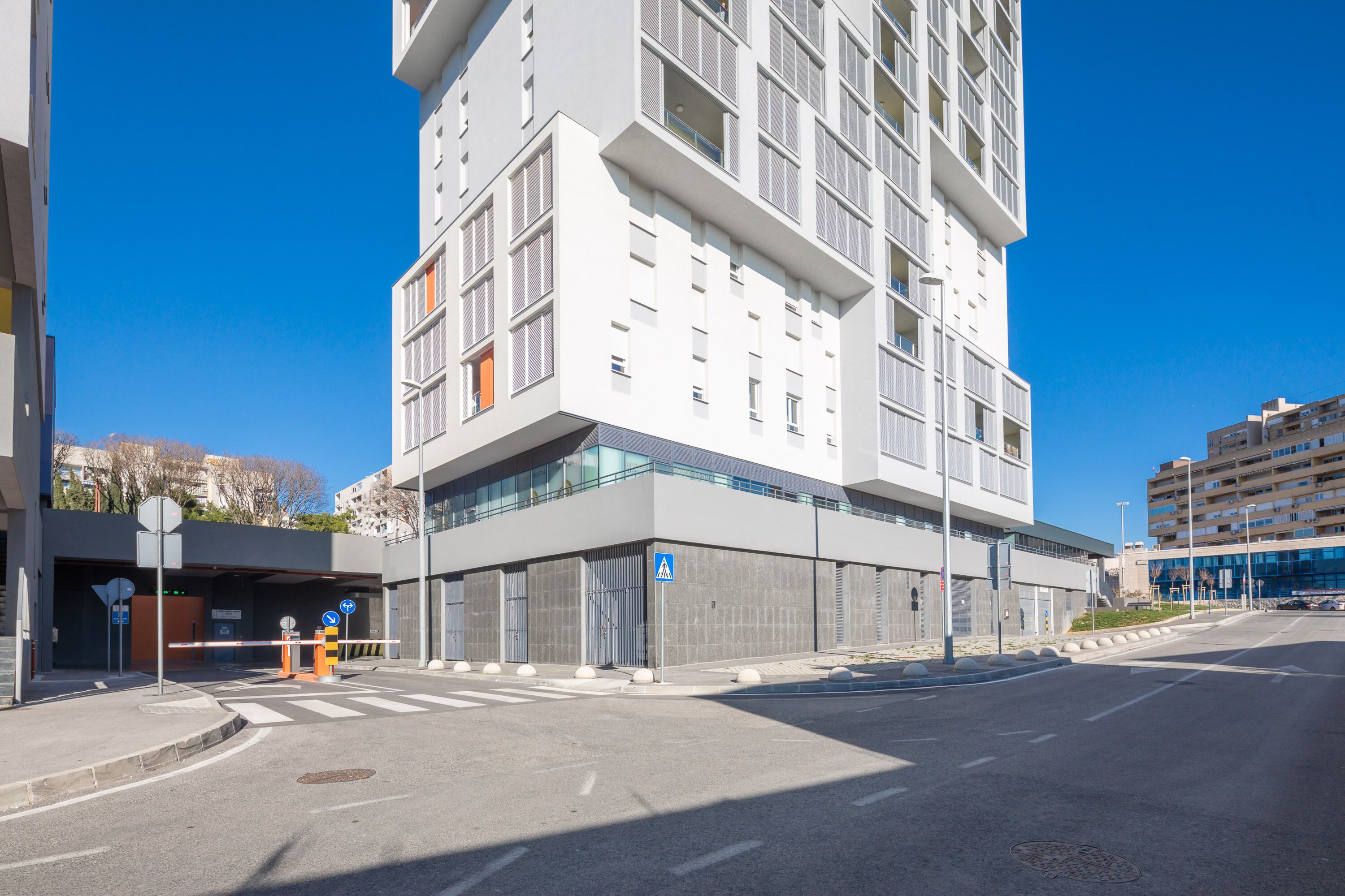 Un edificio moderno con fachada plana, ventanas amplias y una entrada protegida por una puerta.