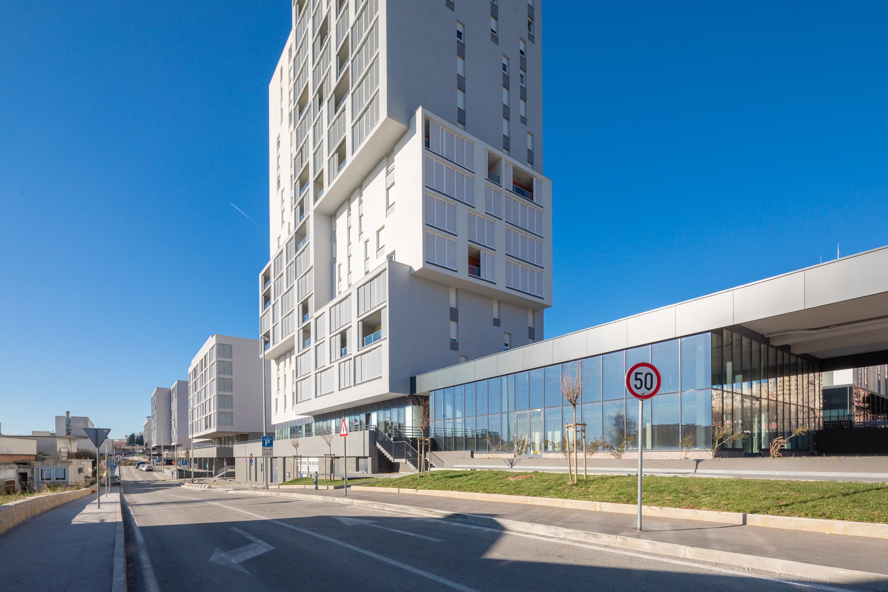 Un bâtiment moderne doté d’une façade en verre et d’un panneau indiquant une limitation de vitesse à 50.