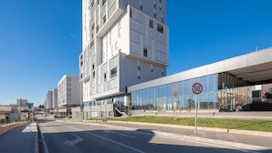 Um edifício moderno com fachada de vidro e placa de limite de velocidade de 50.