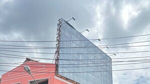 A red building with a large billboard, a sign for Praew Mansion, and a restaurant with outdoor seating. - Praew Mansion (Kamala)