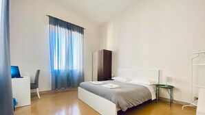 A modern hotel room with a large bed, a desk, and a wardrobe. - Mamamia City (Palermo)