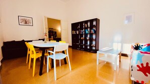 A living room with a round table, yellow and white chairs, a black bookshelf, and a couch. - Mamamia City (Palermo)