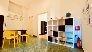 A hotel lobby with a reception desk, a yellow chair, a white bookshelf, and a fire extinguisher. - Mamamia City (Palermo)