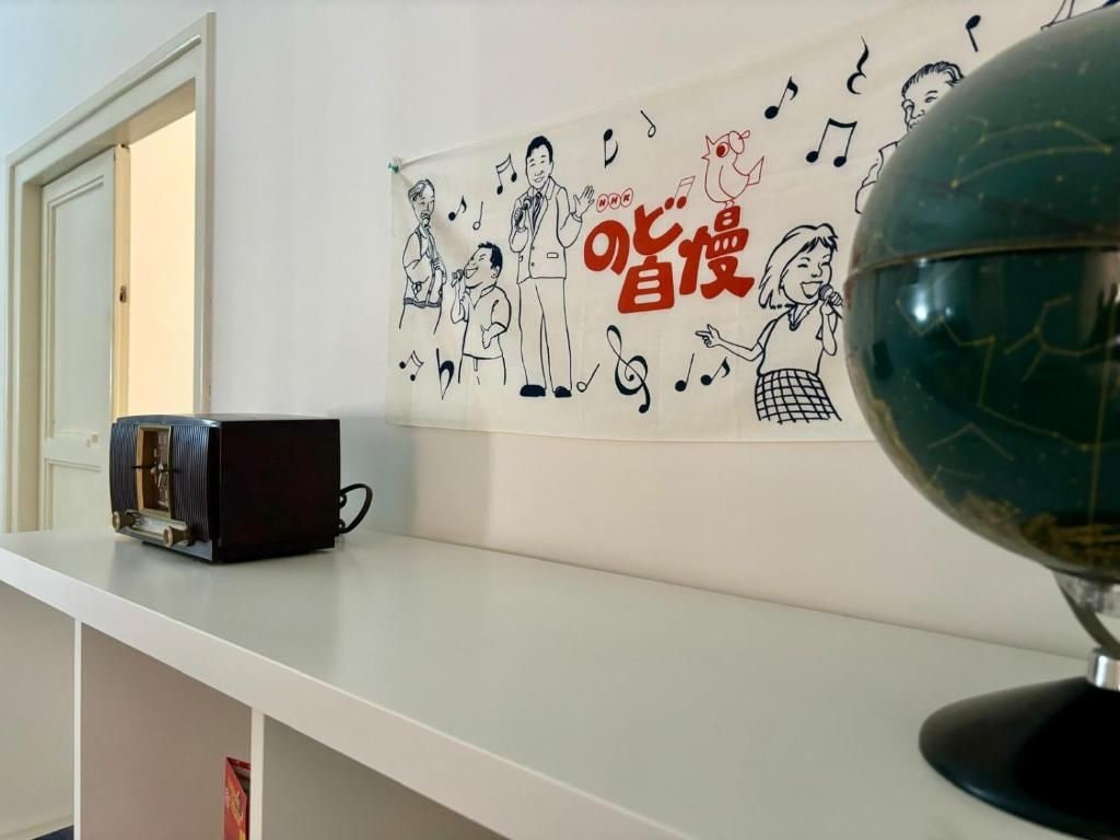 A room with a white shelf, a globe, and a wall with a drawing of people and musical notes.
