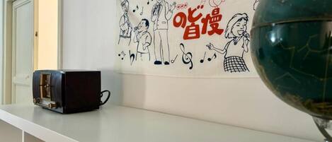 A room with a white shelf, a globe, and a wall with a drawing of people and musical notes.