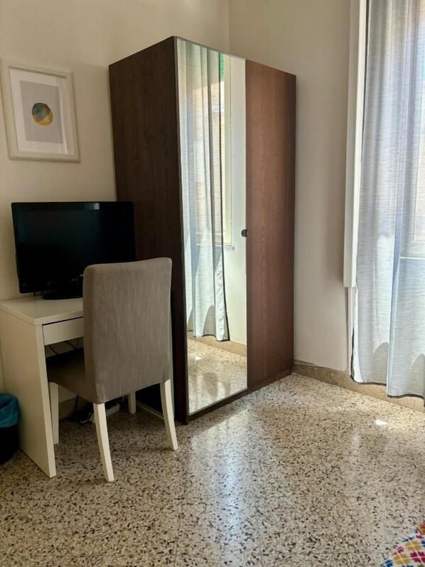 Una habitación con televisión, armario y una silla.