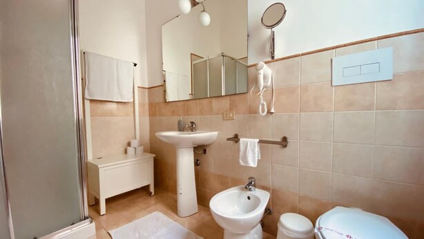 A modern bathroom with a shower, sink, bidet, toilet, and a mirror. - Mamamia City (Palermo)