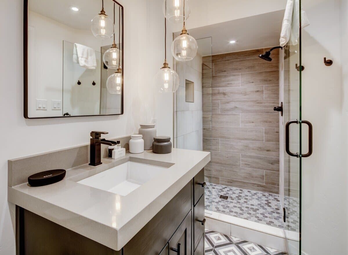 Une salle de bain moderne avec un grand miroir, deux lavabos et un espace douche.