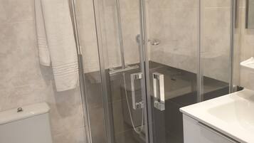 Eenpersoonskamer | Badkamer | Een douche, een haardroger, handdoeken, zeep