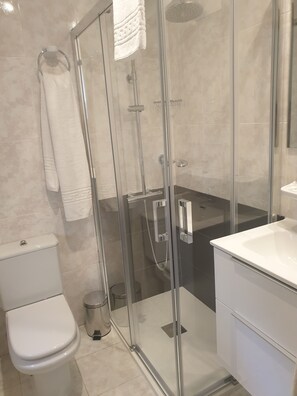 Une salle de bain moderne avec une douche à parois de verre, des toilettes blanches et un lavabo blanc.