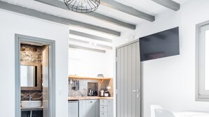 A modern kitchen with white cabinets, a built-in oven, and a large window. - White and Grey (Mykonos)
