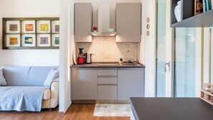 A compact kitchen with modern appliances, a built-in oven, and a coffee machine. - B&B Kapì Country (Alghero)