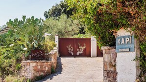 A gated entrance with a cactus plant, a stone wall, and a signboard. - B&B Kapì Country (Alghero)
