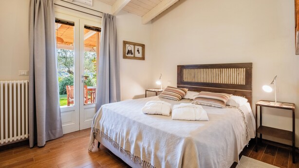 A bedroom with a bed, bedside tables, a radiator, and a view of the outdoors. - B&B Kapì Country (Alghero)