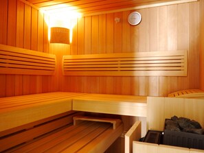 Una sauna con bancos de madera y un calentador en la pared.