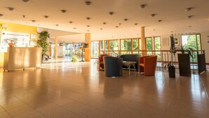 Een ruime lobby met een receptiebalie, zithoek en grote ramen voor veel daglicht.