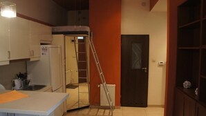 A compact kitchen with white cabinets, a small countertop, and a ladder leaning against a wall.