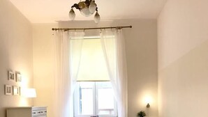 A small, well-lit room with a sofa, a chair, a table, and a radiator.