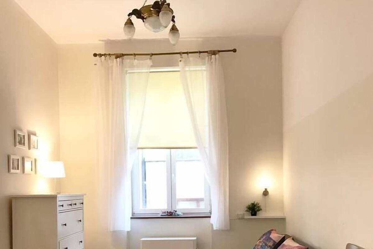 A small, well-lit room with a sofa, a chair, a table, and a radiator.