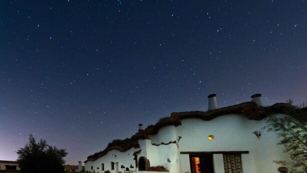 A row of white houses with thatched roofs under a starry night sky. - Las Chumberas Cave - Los Cerezos (Benalua)