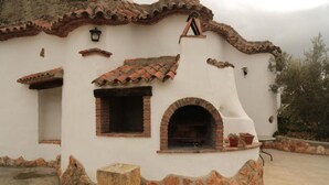 A building with a rustic exterior, featuring a brick oven and a small window. - Las Chumberas Cave - Los Cerezos (Benalua)