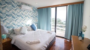 A hotel room with a bed, a nightstand, a desk, and a large window with curtains. - Dojo pool villa beach front and sea view (Unknown)