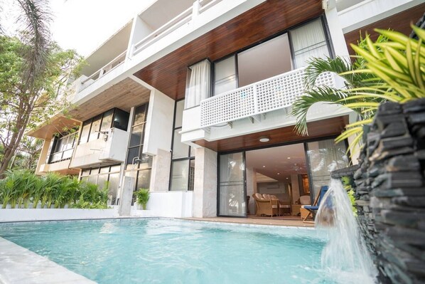 Un bâtiment moderne à deux étages, avec une piscine en premier plan.