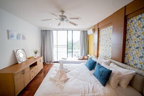 Une chambre d’hôtel moderne dotée d’un grand lit, d’un ventilateur de plafond, d’une vue sur l’extérieur et d’une commode en bois.