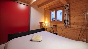 A bedroom with a bed, a desk, and a window with curtains. - B&B - La Case A Kio Bourg-St-Maurice Les Arcs (Les Chapelles)