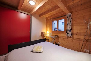 Un dormitorio con cama, escritorio y ventana con cortinas.